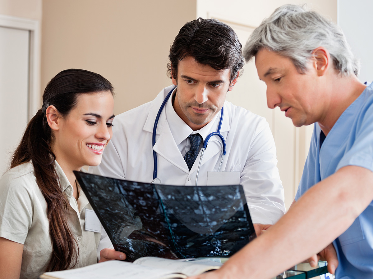 1200x900GMB-2 Medical professionals reviewing x-ray at hospital reception.
