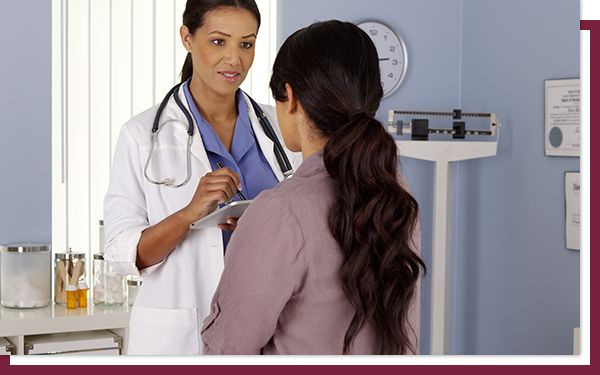 IMG 2 A female doctor talking to a woman who is sitting in her medical office.