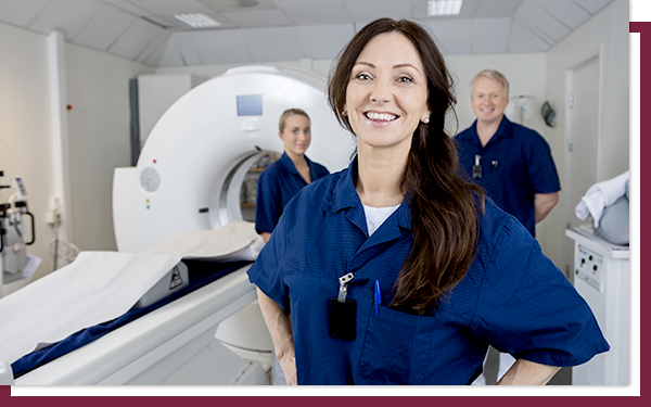 IMG 3 Three medical technicians standing in front of an MRI machine and smiling.