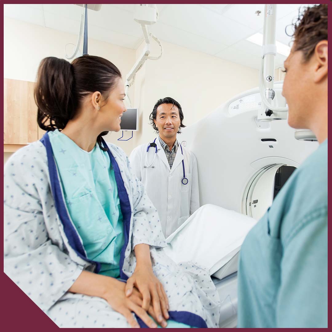 Image-1 A woman sits on an imaging table speaking with a doctor and a nurse.