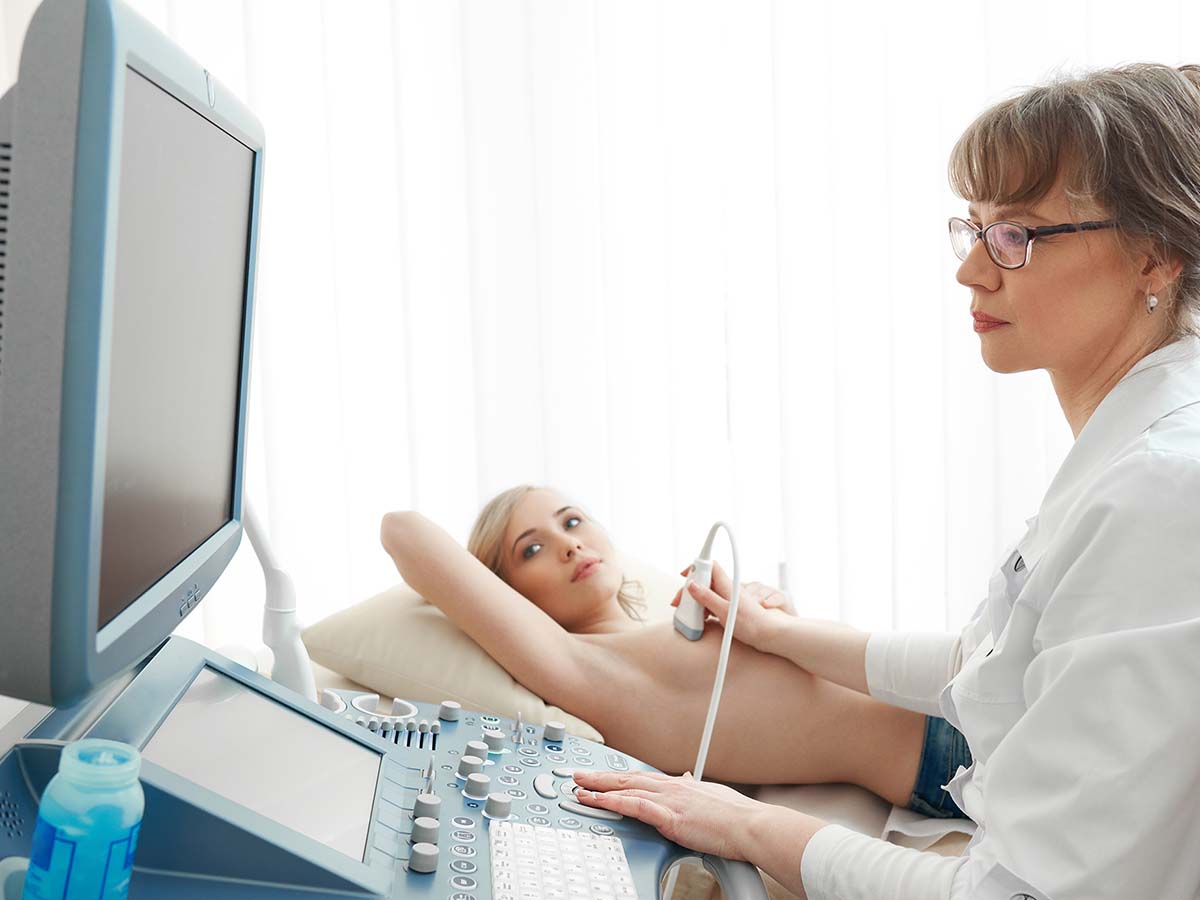 1200x900GMB-4 Female doctor performing a breast ultrasound on a middle-aged patient.