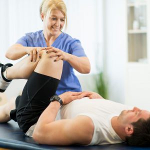 A woman helping a man with physical therapy.